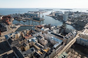 An aerial view of a coastal city with a marina, dense urban buildings, and a prominent bridge.