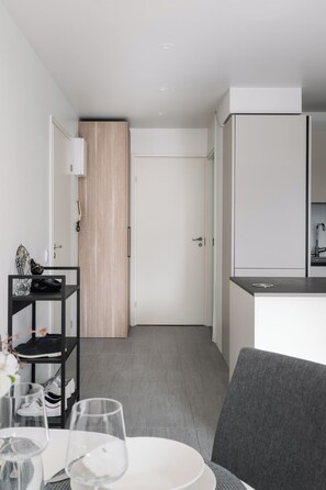 A modern kitchen with white cabinets, a grey countertop, and a wooden door.