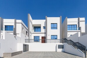 A modern multi-story building with a flat roof, large windows, and a central staircase. - Pool, Mountain & Sea View 6BR Villa w/ Asst & Driver Room,Heated Pool,BBQ Area (Fujairah)