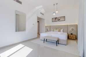 A modern bedroom with a large bed, bedside tables, a bench, and artwork on the wall. - Pool, Mountain & Sea View 6BR Villa w/ Asst & Driver Room,Heated Pool,BBQ Area (Fujairah)