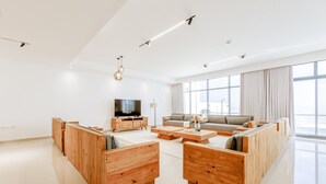 Un salón amplio con un televisor grande, muebles de madera y ventanas grandes.