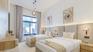 Habitación de hotel con dos camas, una mesita de noche de madera y un gran ventanal con cortinas.