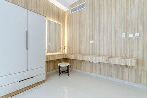 A modern bathroom with a wooden vanity, a white stool, and a large mirror.