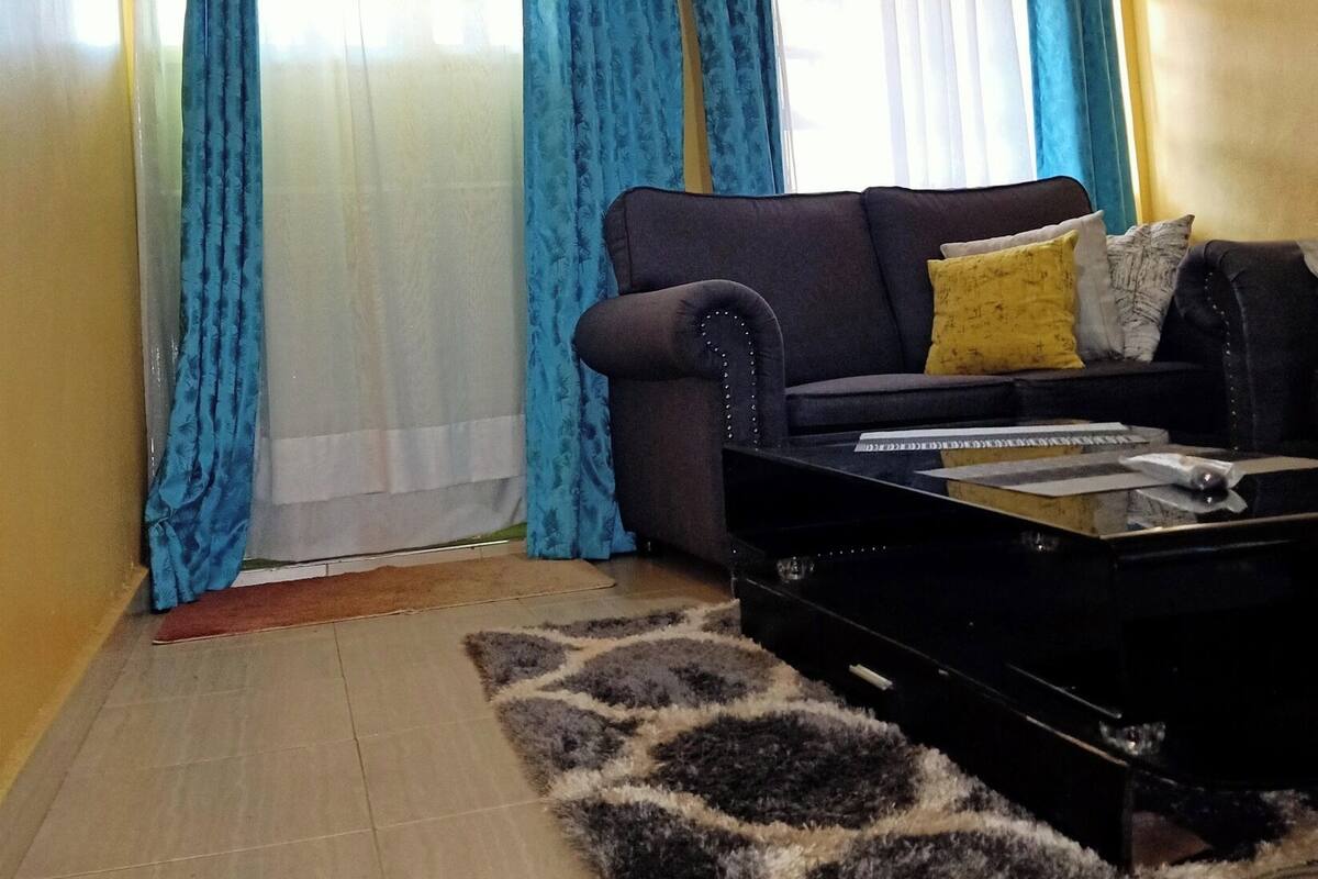 Uma sala de estar com sofá, mesa de centro e cortinas azuis.