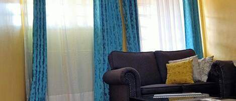 A living room with a sofa, a coffee table, and blue curtains.