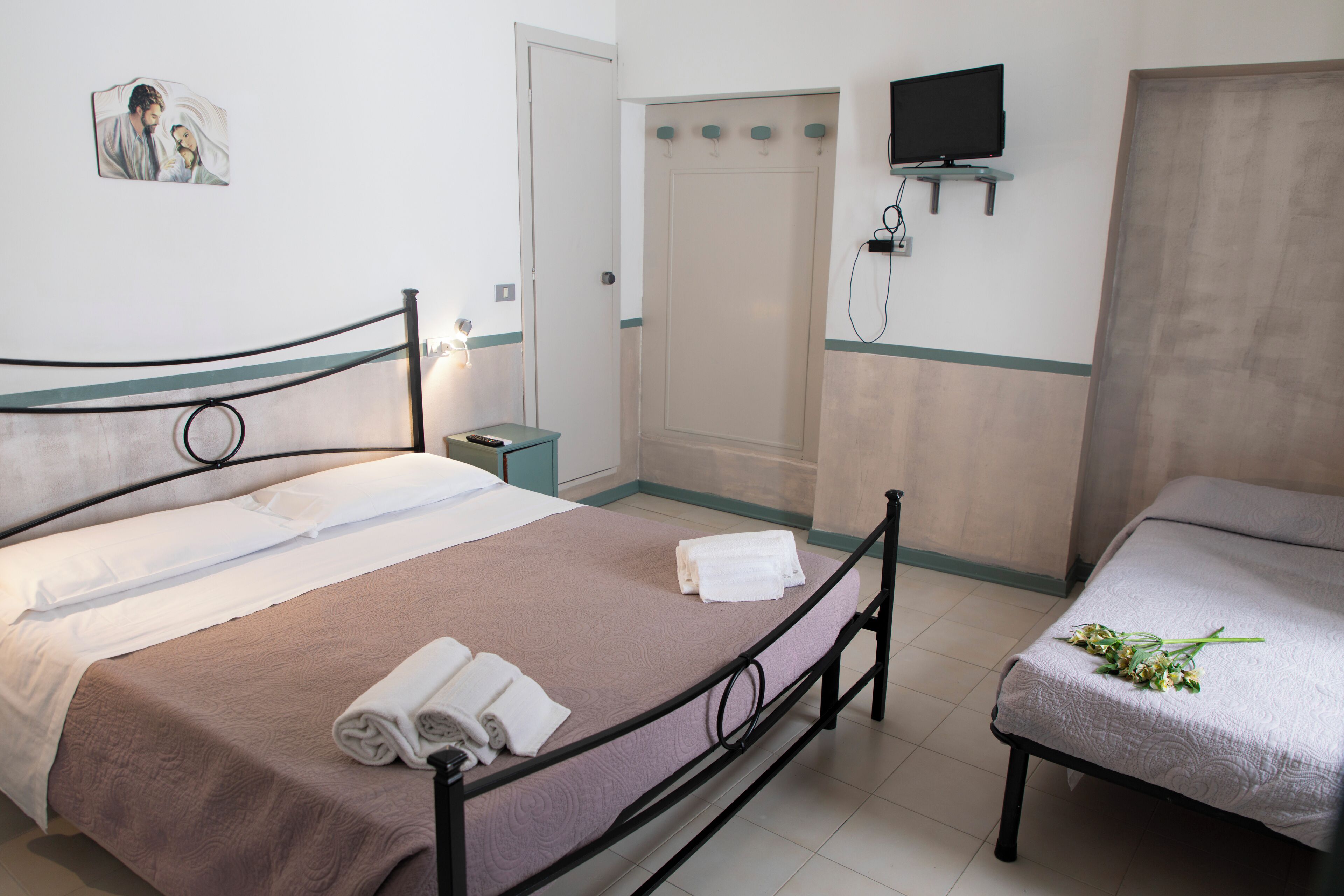 A hotel room with two beds, a TV mounted on the wall, and a door leading to a bathroom.