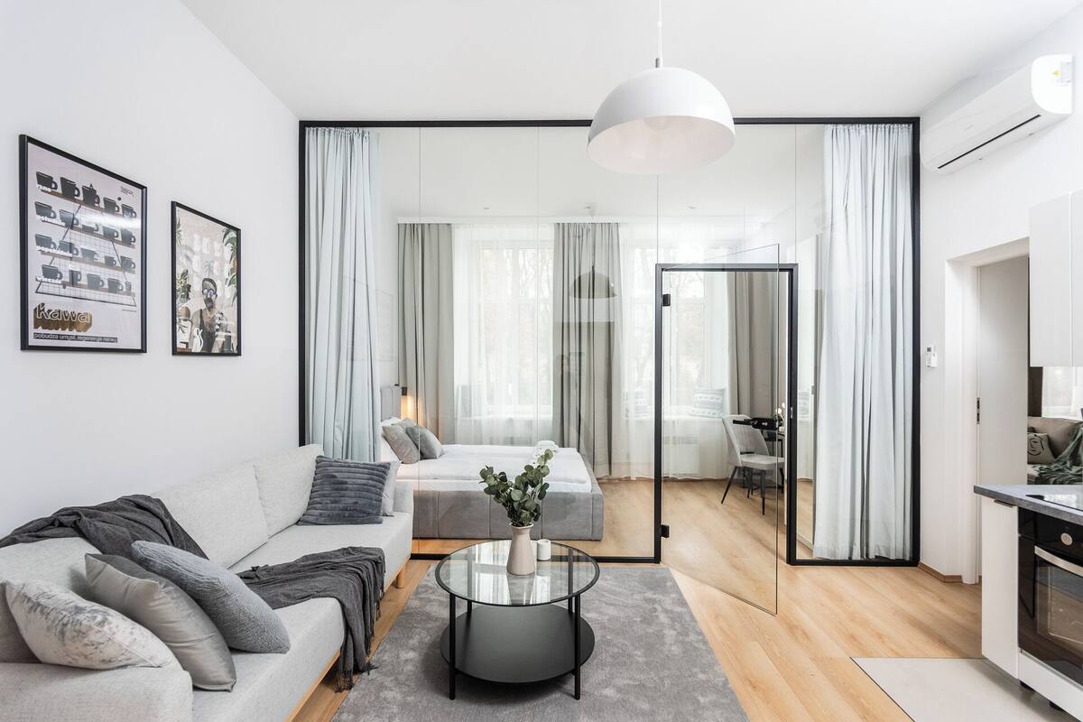 Un salon moderne avec un canapé, une table basse et un coin repas visible à travers une porte vitrée.