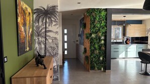 A modern interior with a wooden reception desk, a wall with a tropical mural, and a green vertical garden.