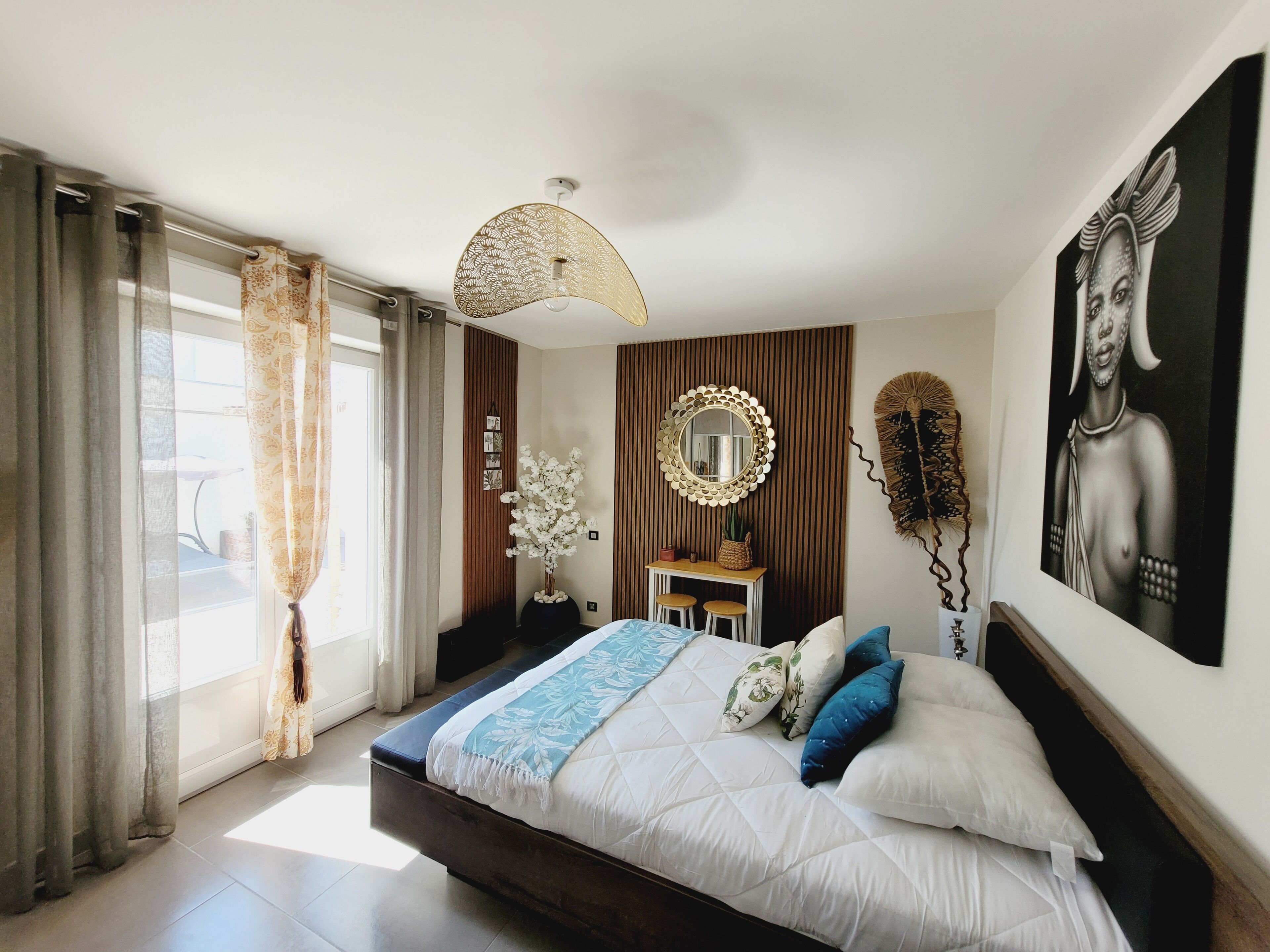 A modern bedroom with a large bed, a desk, a mirror, and artwork on the walls.