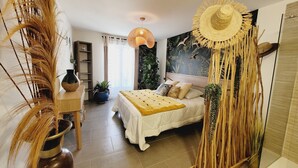 A bedroom with a bed, bedside table, and a hanging chair.