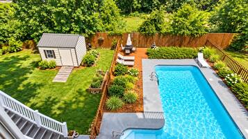 A backyard with a swimming pool, a small shed, and a wooden deck.