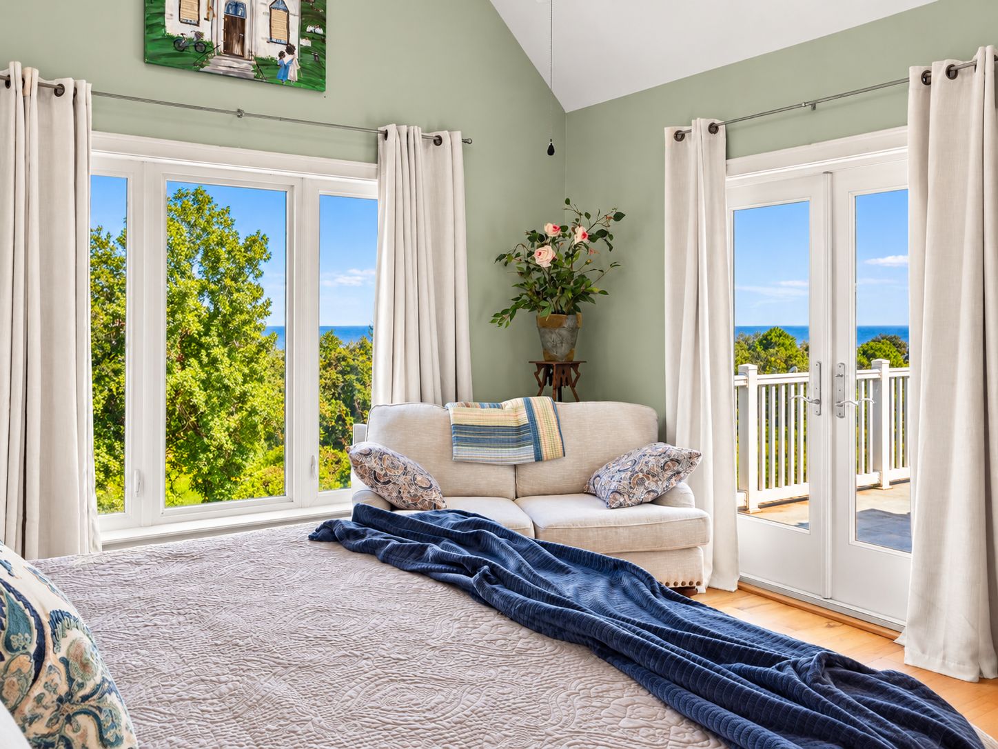 A bedroom with a large bed, a sofa, and a view of the outdoors.