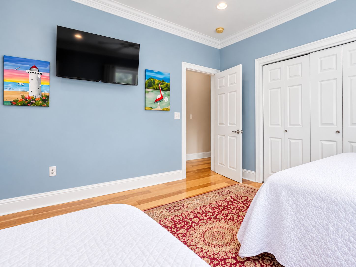 A bedroom with two beds, a TV, and artwork on the wall.