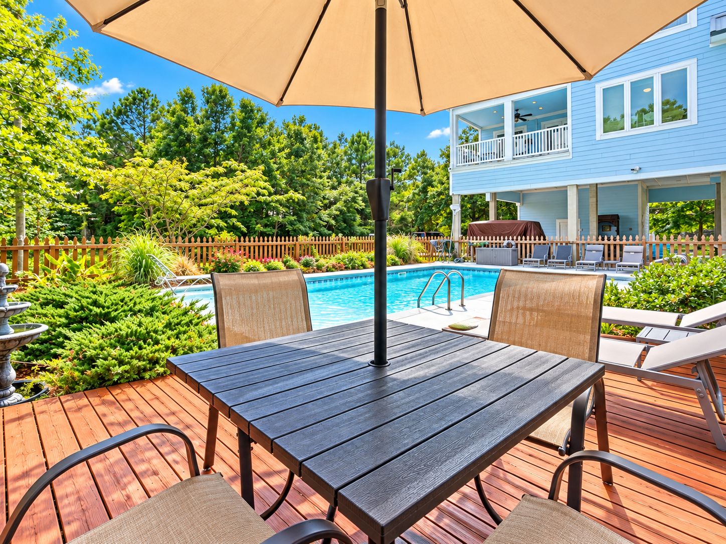 A wooden deck with a pool table, chairs, and an umbrella.