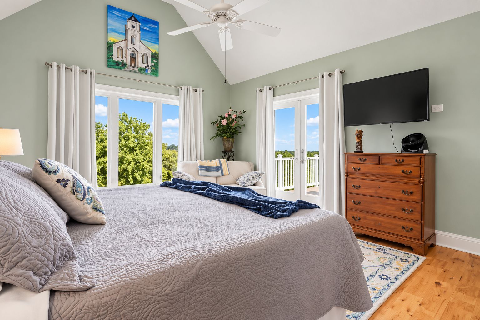 A bedroom with a bed, a dresser, a television, and a window with curtains.