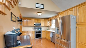 A kitchen with wooden cabinets, stainless steel appliances, and a coffee maker on the counter. - Game Room & On-site Pond: Laurelville Retreat! (Laurelville)