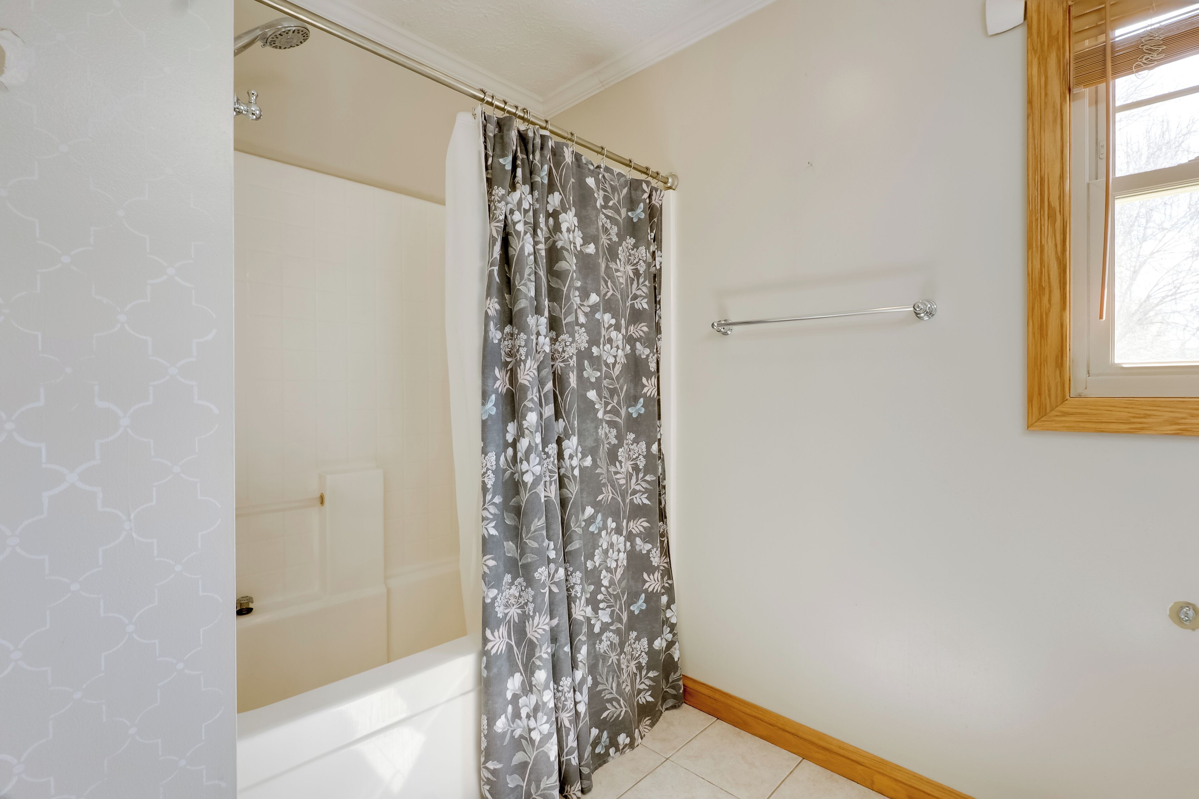 Ein Badezimmer mit Duschvorhang, Handtuchhalter und einem Fenster.
