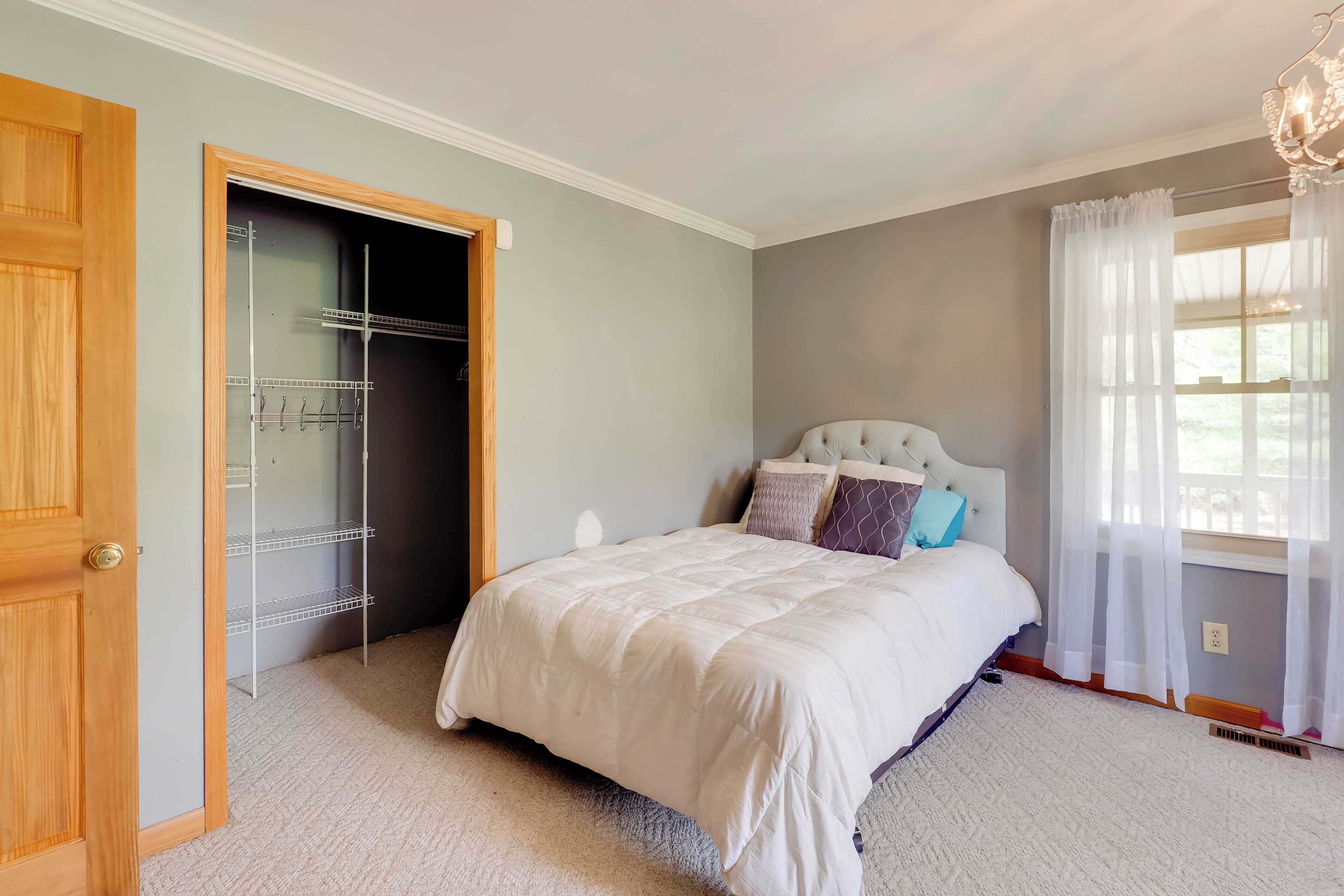A bedroom with a bed, a wardrobe, and a window with curtains.