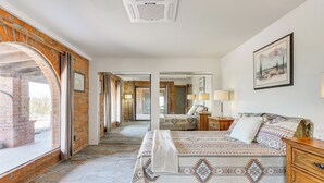 A bedroom with a large bed, a wooden dresser, a nightstand, and a painting on the wall. - 10-acre Desert Oasis w/ Expansive Patio in Tucson! (Tucson)