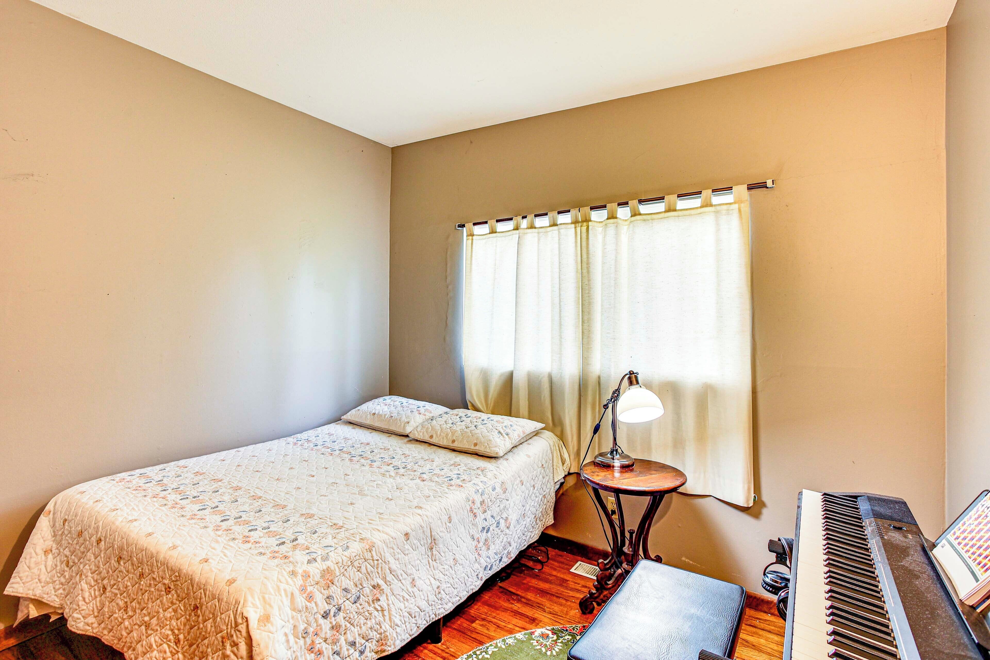 A bedroom with a bed, a piano, and a lamp.