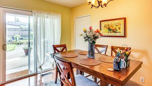 Un coin repas avec une table en bois, des chaises, un vase de fleurs et un tableau accroché au mur.
