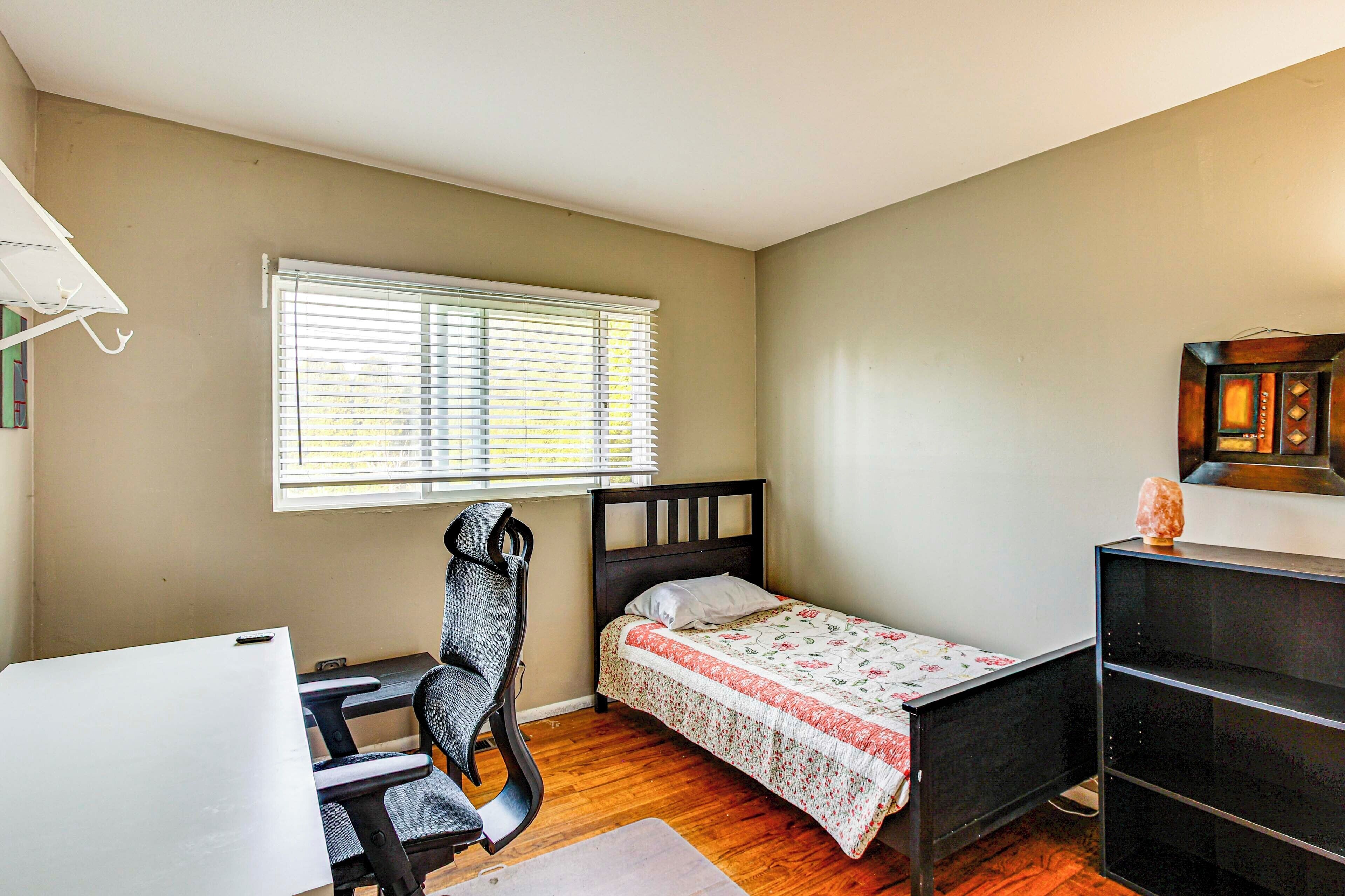 Une chambre avec un lit simple, un bureau et une chaise.