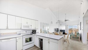 A modern kitchen with white cabinetry, a microwave, an oven, and a coffee maker.