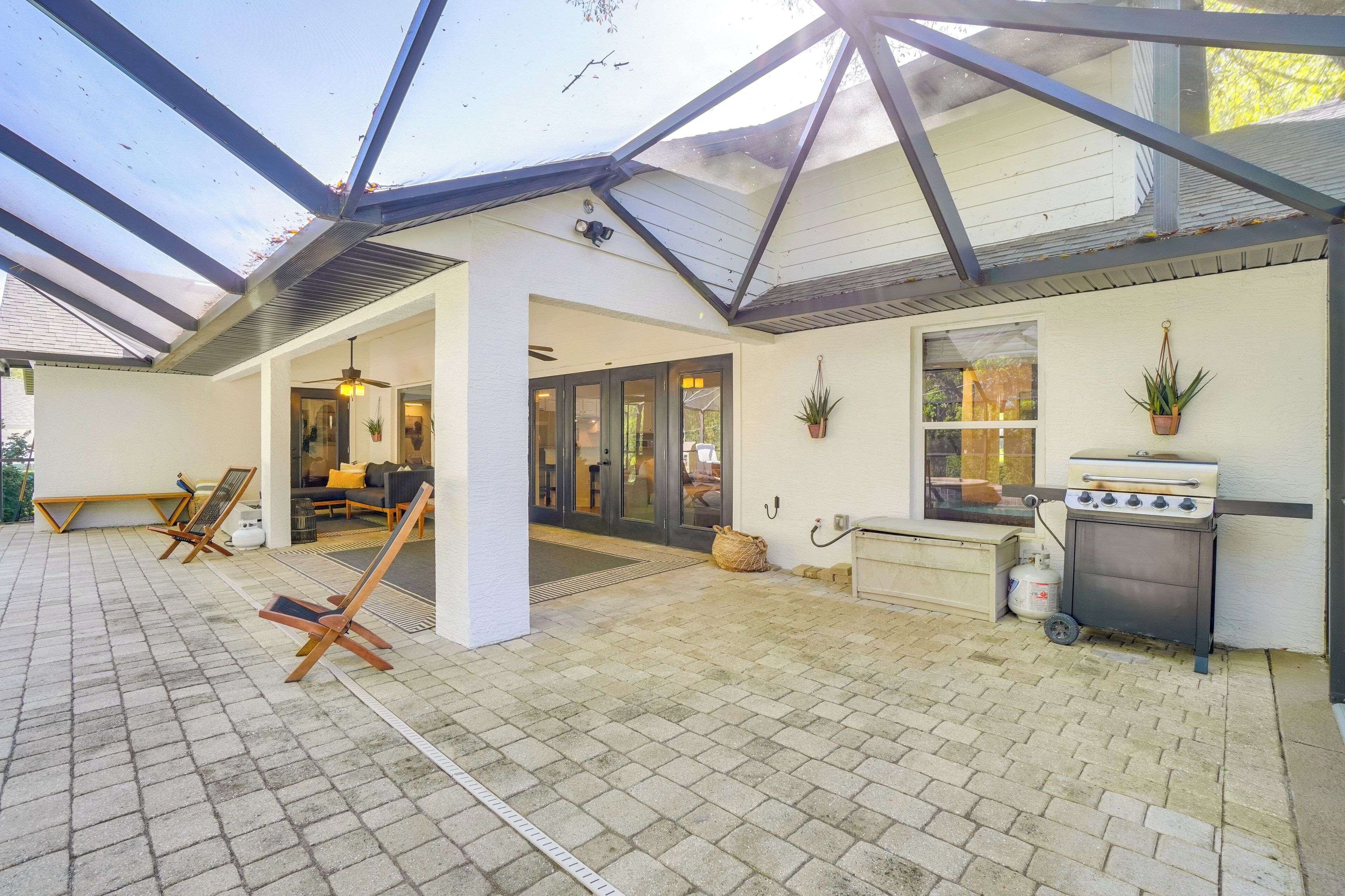 Ein überdachter Patio-Bereich mit Grill, Sitzgelegenheiten und Blick auf das Haus.