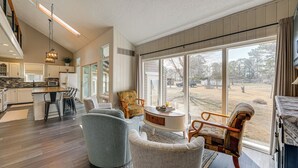 A spacious living room with a large window, a kitchen in the background, and a dining area with chairs and a table. - Private Beach & Fishing Pier: Wicomico River House (Princess Anne)