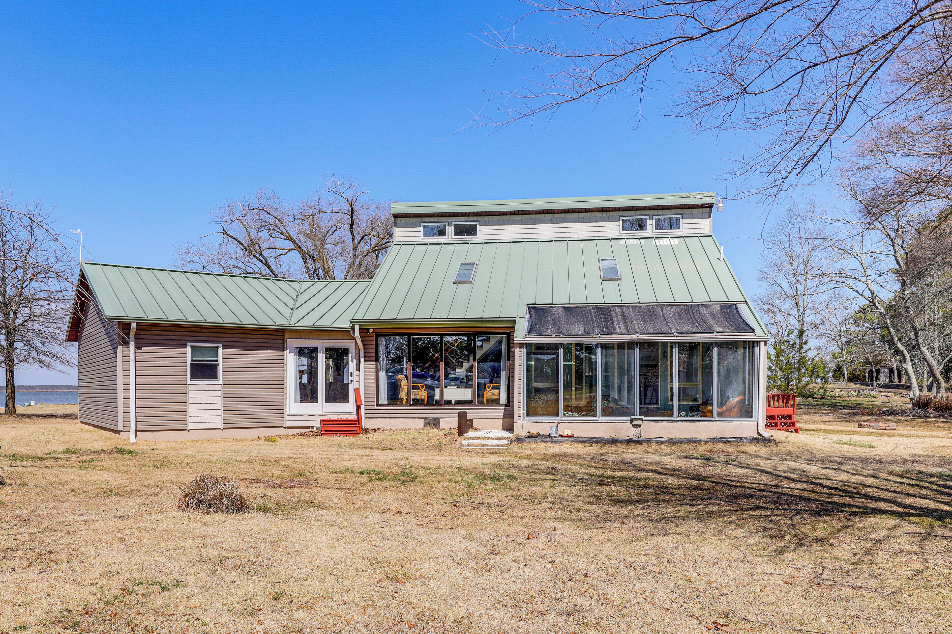 A two-story building with a green roof, large windows, and a covered porch.