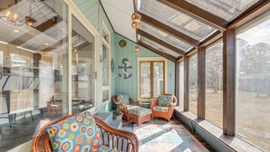 A sunlit room with wicker furniture, large windows, and a view of the outdoors. - Private Beach & Fishing Pier: Wicomico River House (Princess Anne)