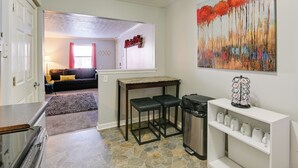 A kitchen with a stone tile floor, a wooden table with two stools, a trash can, and a white cabinet with shelves. - 1 Mi to Dtwn: Pet-friendly Apt in Nashville (Nashville)