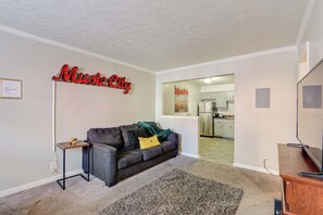 A living room with a gray sofa, a small side table, a patterned rug, and a TV stand. - 1 Mi to Dtwn: Pet-friendly Apt in Nashville (Nashville)