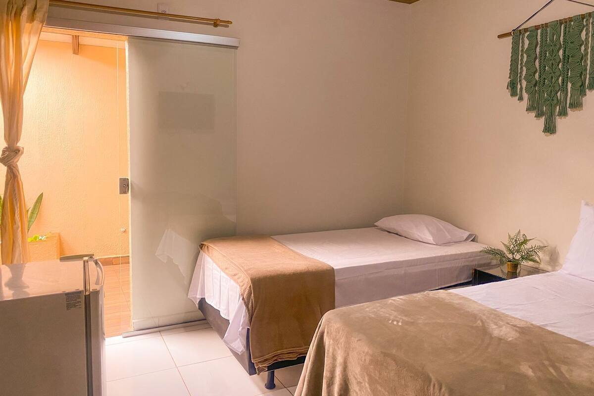 Une petite chambre, de taille modeste, comprenant deux lits simples, une petite table et une porte donnant sur une salle de bain.