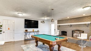 A pool table in a room with a brick fireplace, a television, and a bar area. - 4 Mi to Wku: Hilltopper's Hideaway w/ Grills! (Bowling Green)