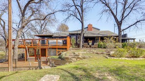 A two-story building with a glass balcony, surrounded by trees and a grassy area. - Creekside Cottage w/ Deck & Hot Tub in Belton (Belton)