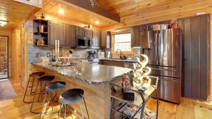 Una cocina moderna con electrodomésticos de acero inoxidable, armarios de madera y una isla central con taburetes de bar.