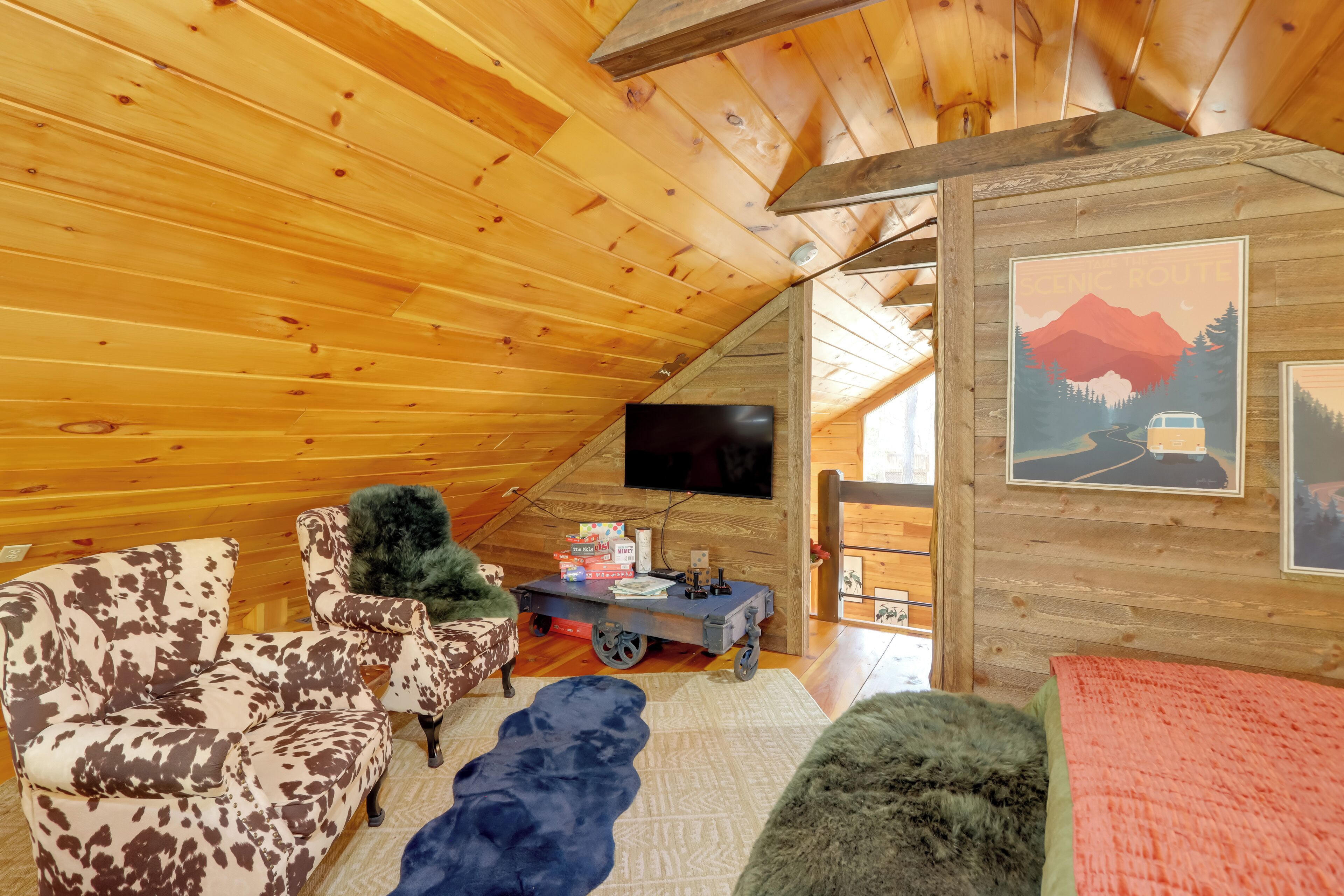 A cozy cabin with a wooden interior, a television, a sofa, a chair, and a cart with boxes.