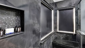 A modern bathroom with a stone wall, a built-in shelf with toiletries, and a large mirror. - Private Pool & Hot Tub: 'wild Horse' Home! (College Station)