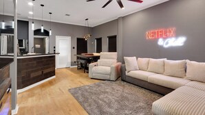 A modern living room with a sectional sofa, a dining area, and a kitchen with a bar. - Private Pool & Hot Tub: 'wild Horse' Home! (College Station)
