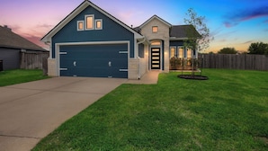 A two-story house with a garage, a front door, and a small tree in the yard. - Private Pool & Hot Tub: 'wild Horse' Home! (College Station)