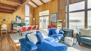 A spacious living area with a large blue sofa, red chairs, and a fireplace. - Decks & Views: Waterfront Shelton Home (Shelton)