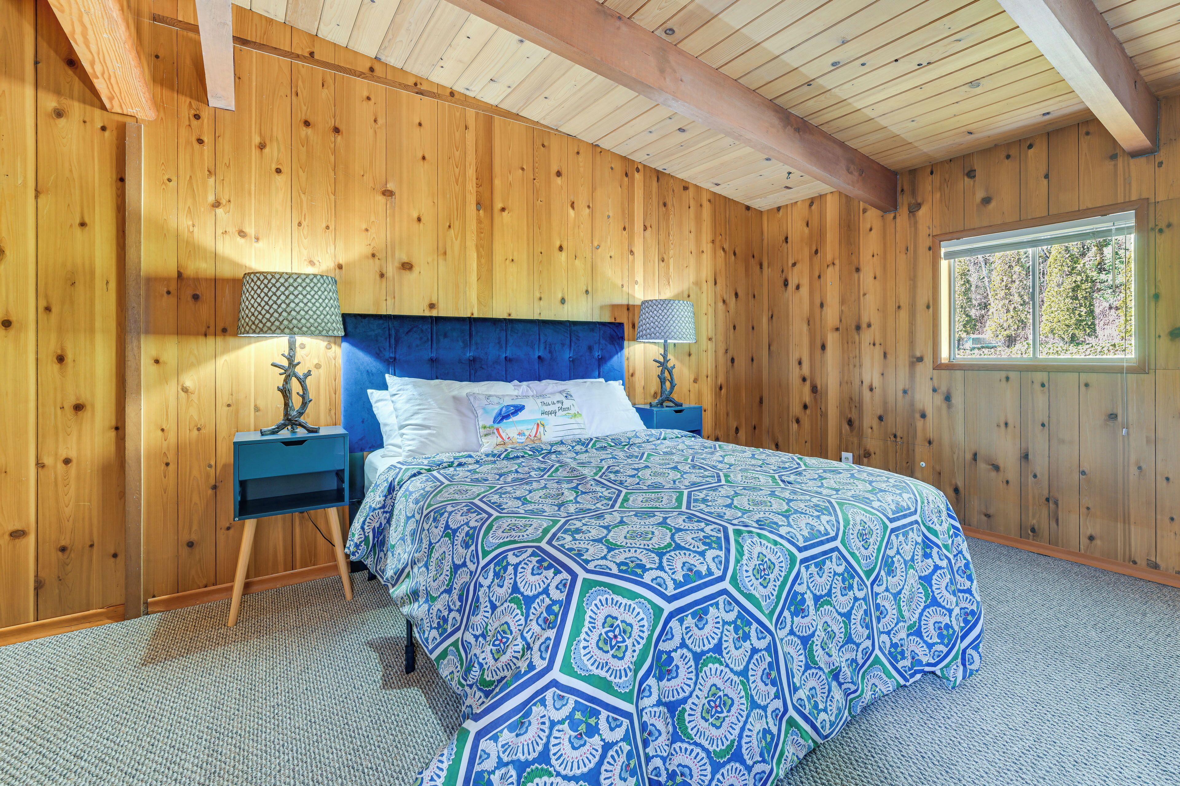 A wooden-paneled bedroom with a large bed, two nightstands, and a window.