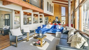 A spacious living area with a blue sofa, black leather chairs, and a wooden ceiling. - Decks & Views: Waterfront Shelton Home (Shelton)