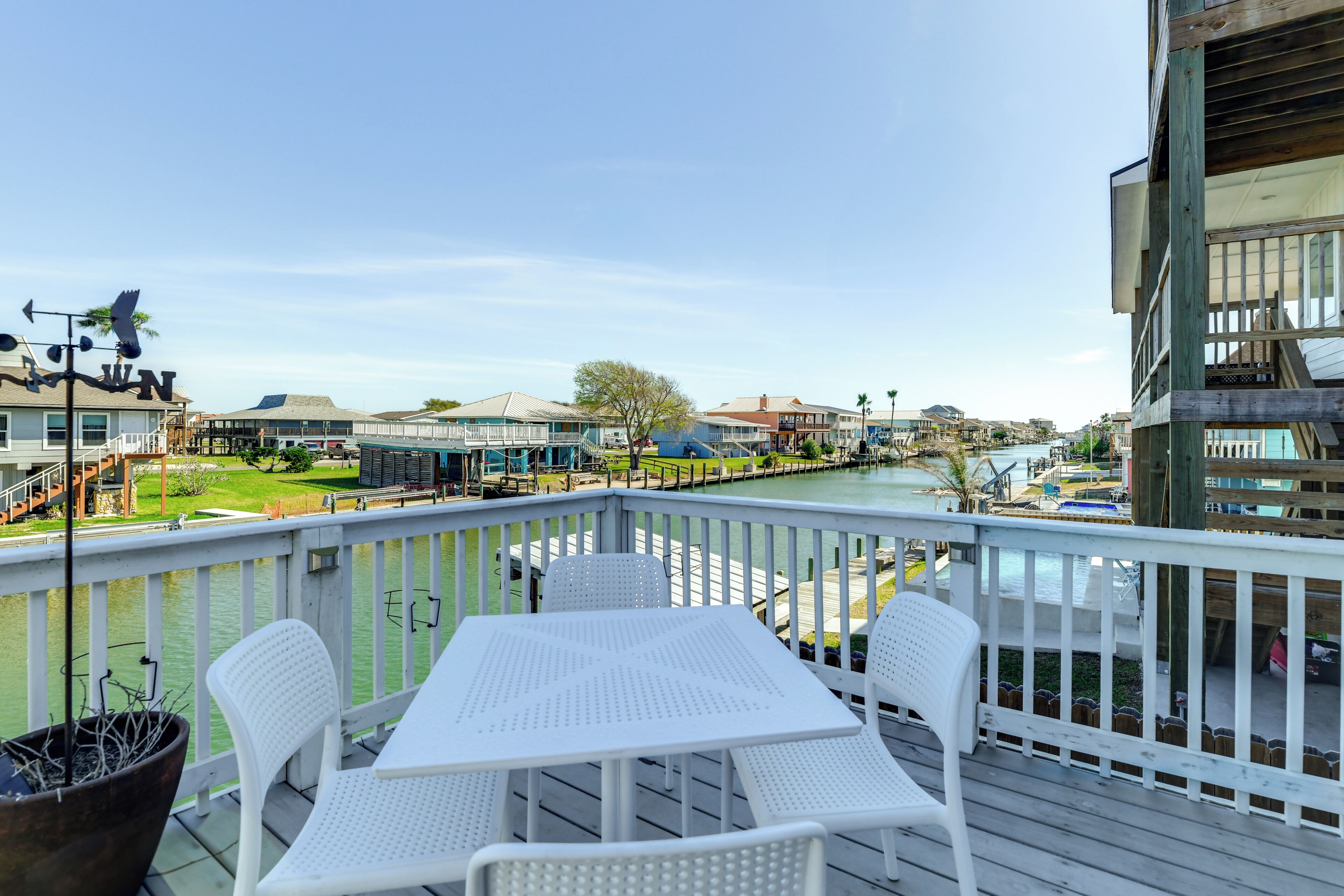 Eine Terrasse mit Tisch und Stühlen mit Blick auf eine Marina, wo Boote und Gebäude liegen.