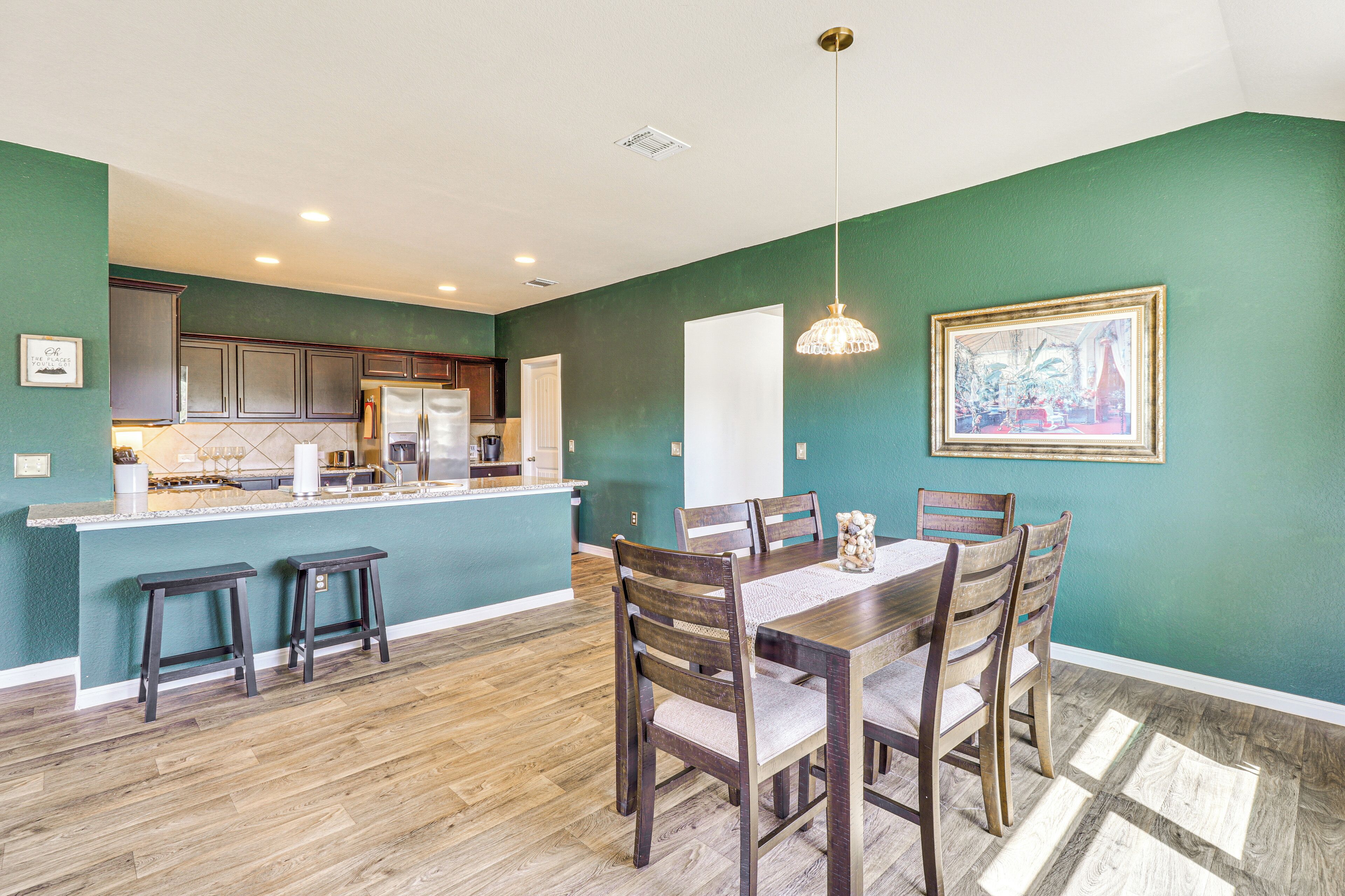 A kitchen with wooden cabinets, a central island, and a dining area with a table and chairs.