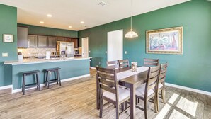 A kitchen with wooden cabinets, a central island, and a dining area with a table and chairs. - Shop, Dine & Unwind: Pet-friendly Home in Austin! (Austin)
