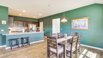A kitchen with wooden cabinets, a central island, and a dining area with a table and chairs.