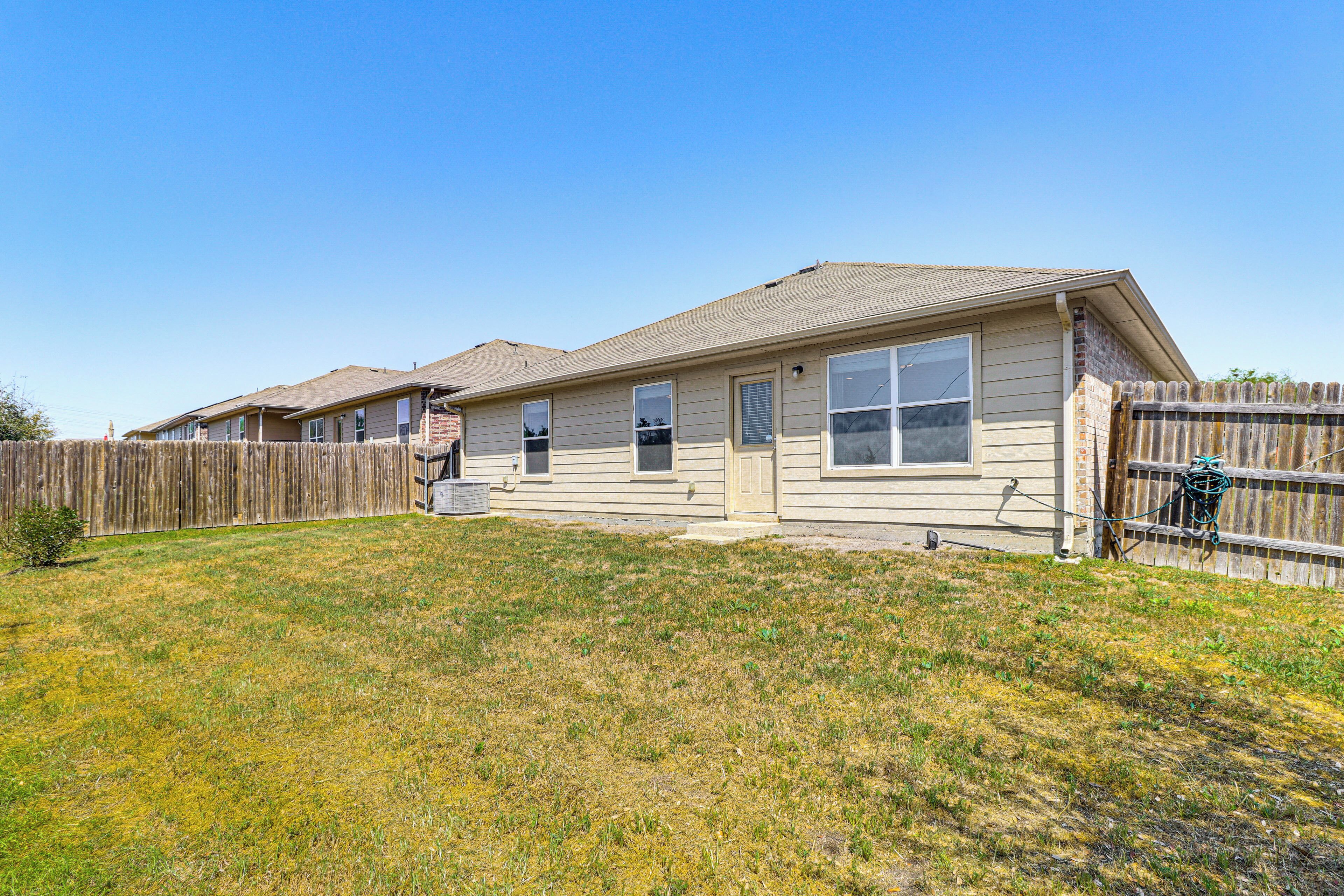 A single-story house with a front yard and a wooden fence.