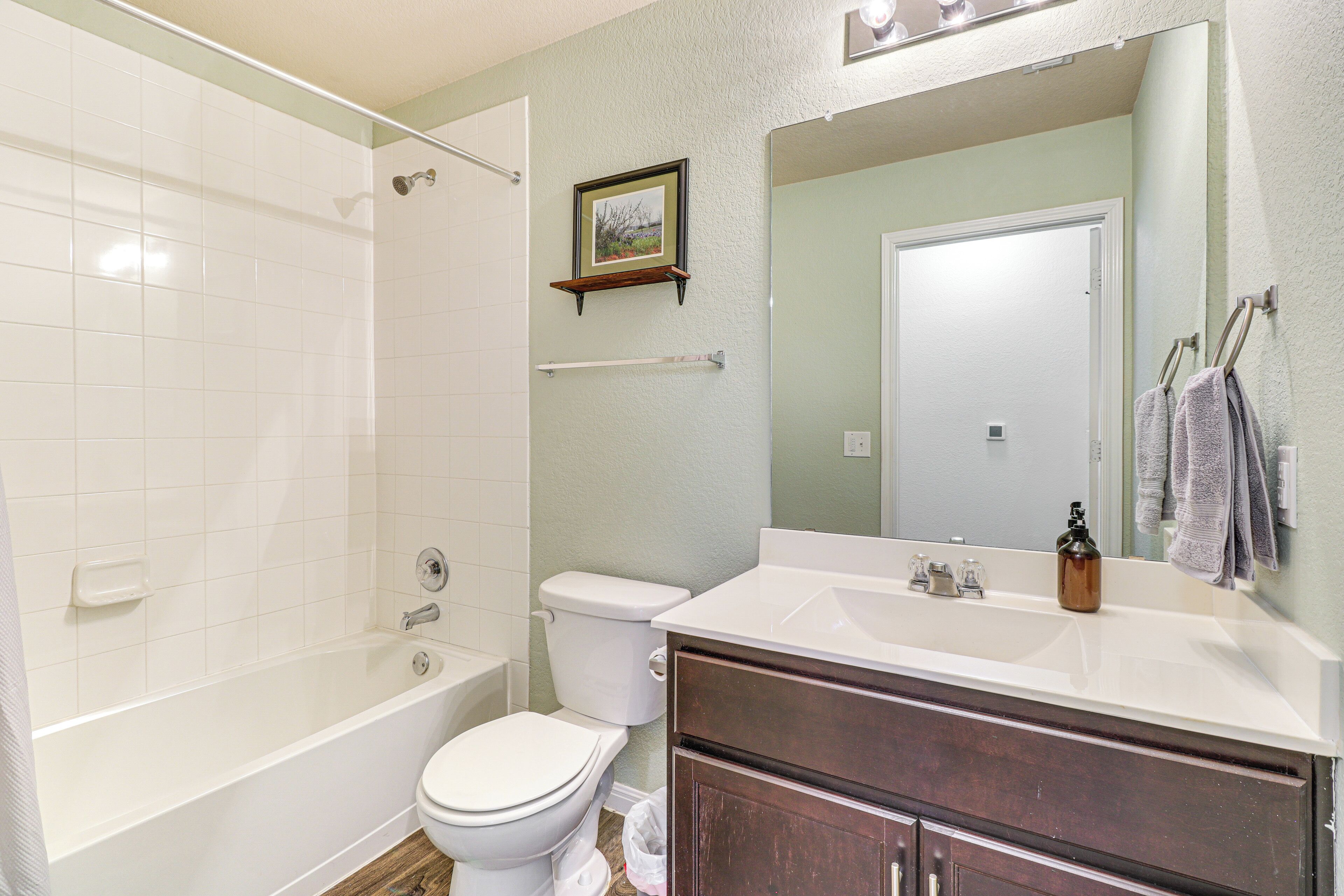 A bathroom with a bathtub, toilet, and vanity with a mirror.